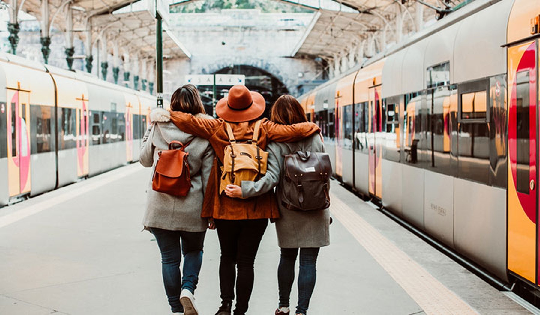 Tres amigos de espaldas en una estación de tren