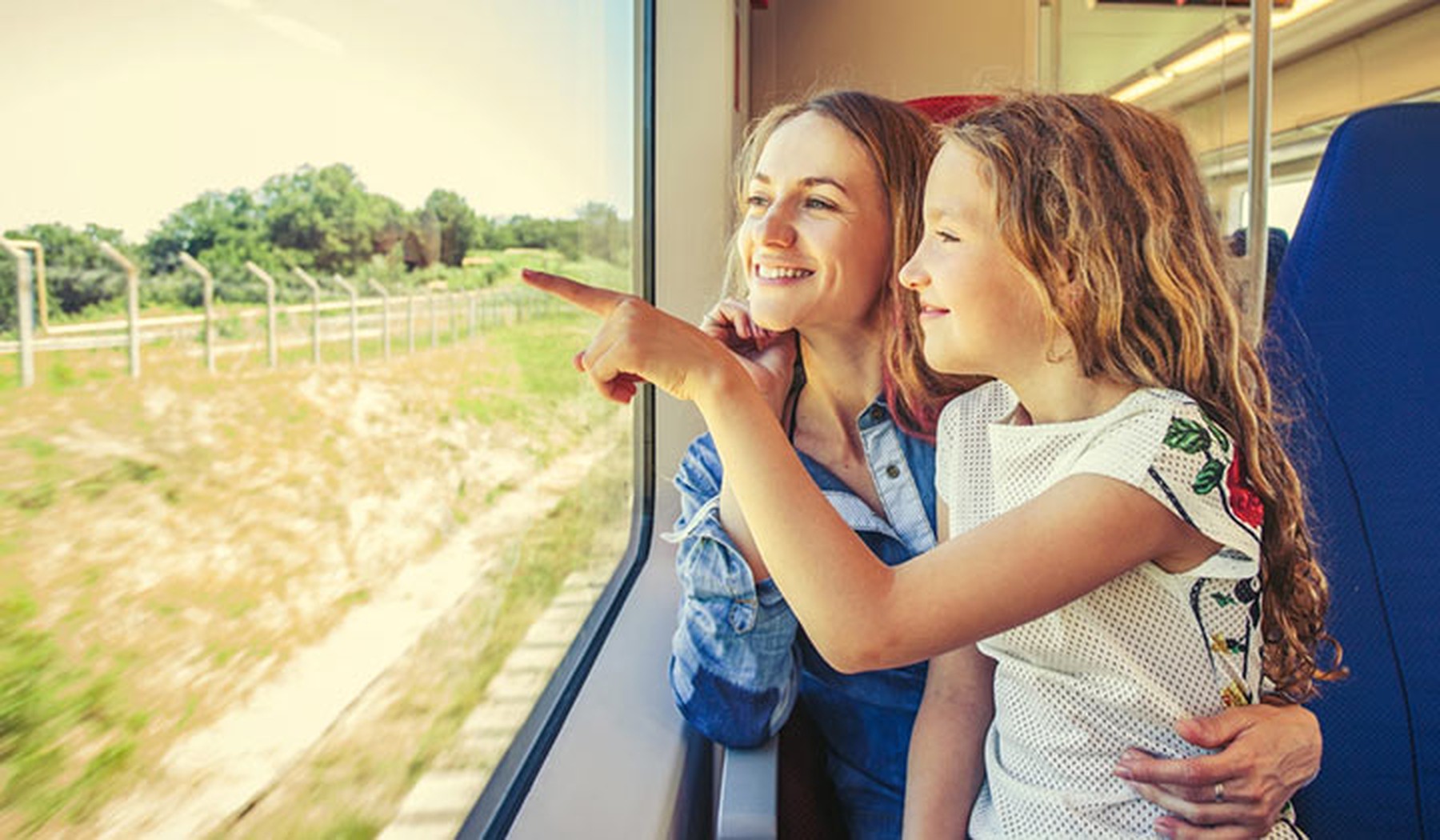 Niña y su madre mirando por la ventana de un tren