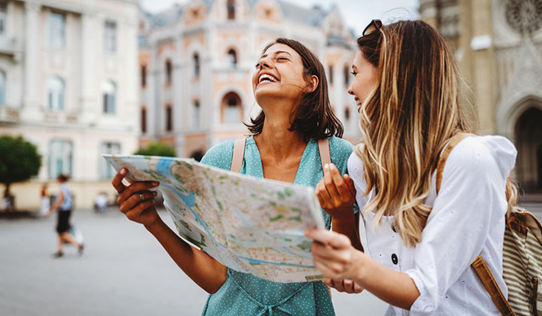 Dos mujeres riéndose y haciendo turismo con un mapa