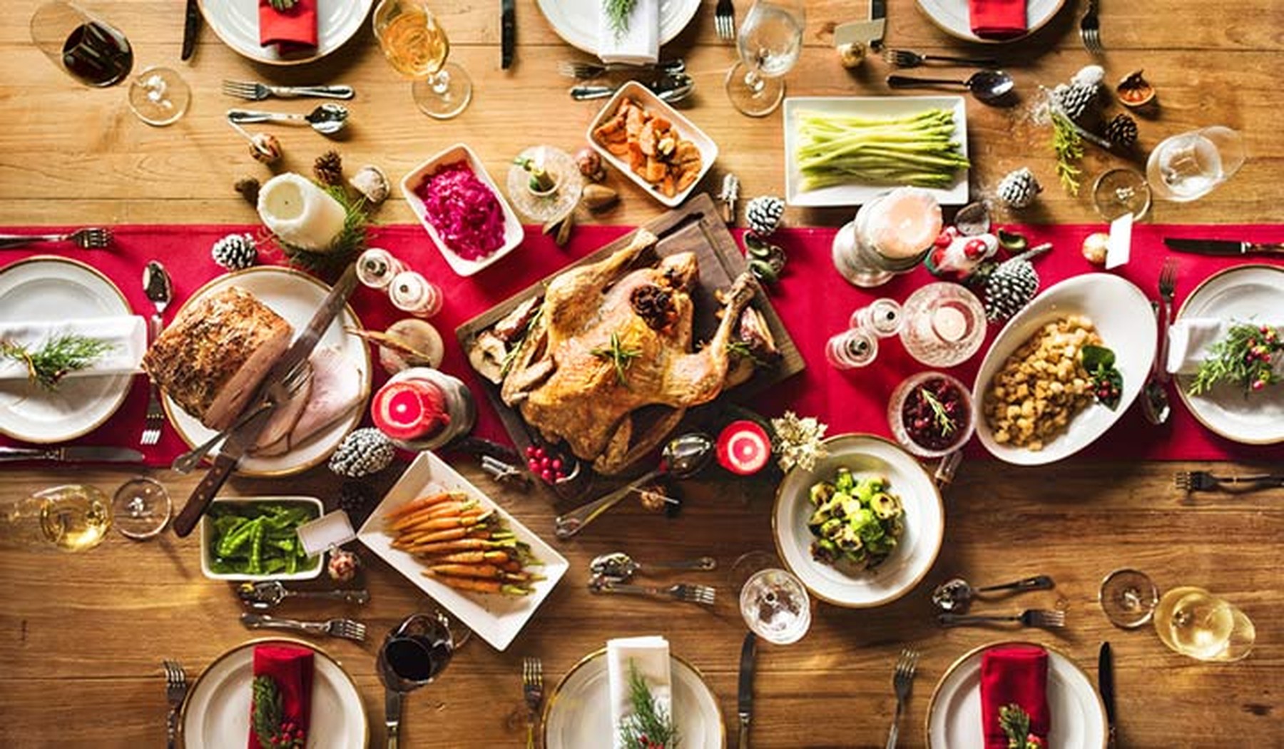 Mesa de navidad con un pavo en el centro, copas de vino, redondo de carne y otros aperitivos