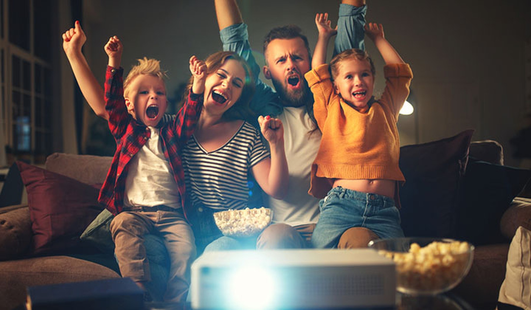 Una familia frente a un proyector disfrutando de una película con palomitas