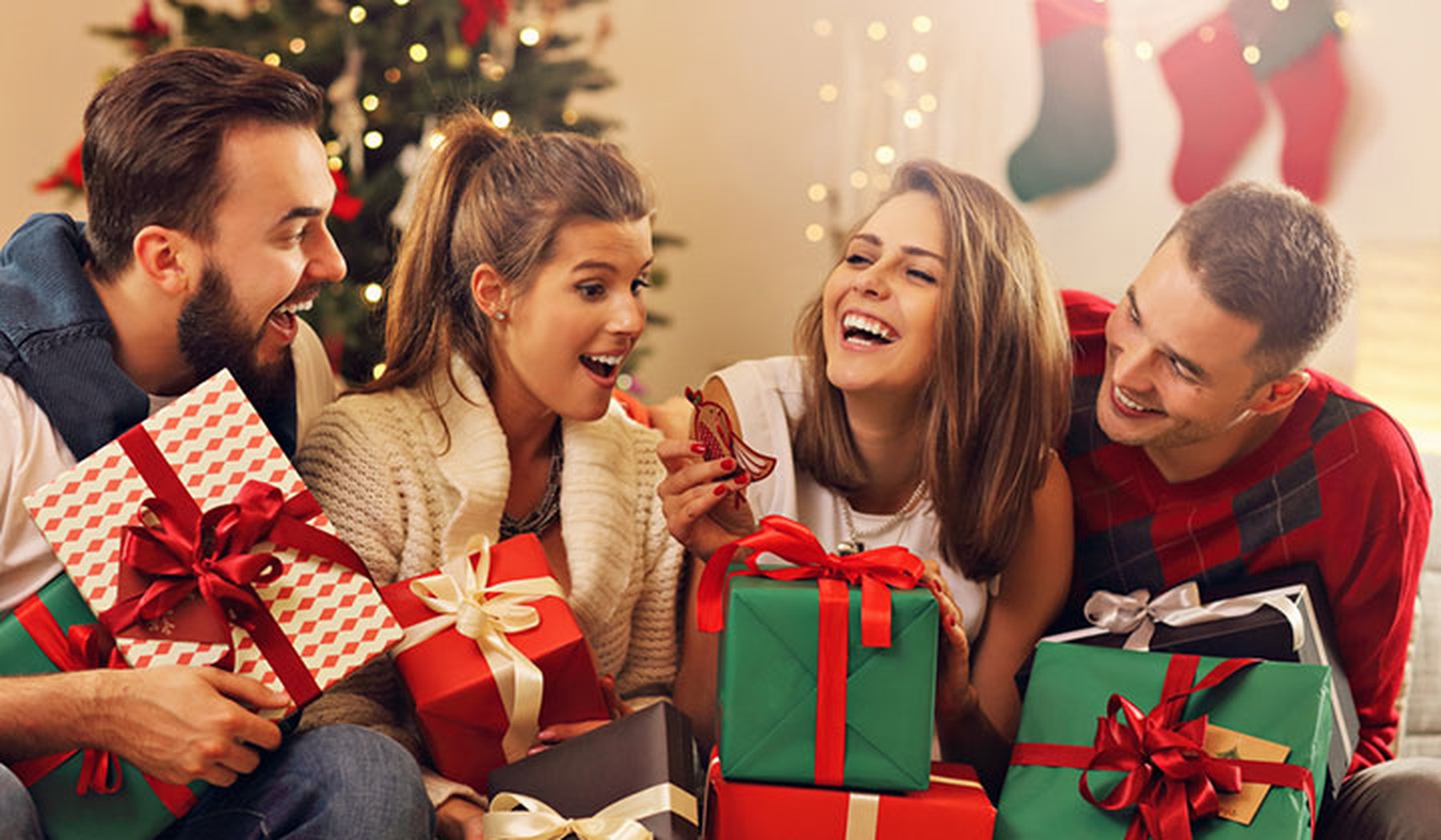 Grupo de amigos con regalos y un árbol de navidad al fondo