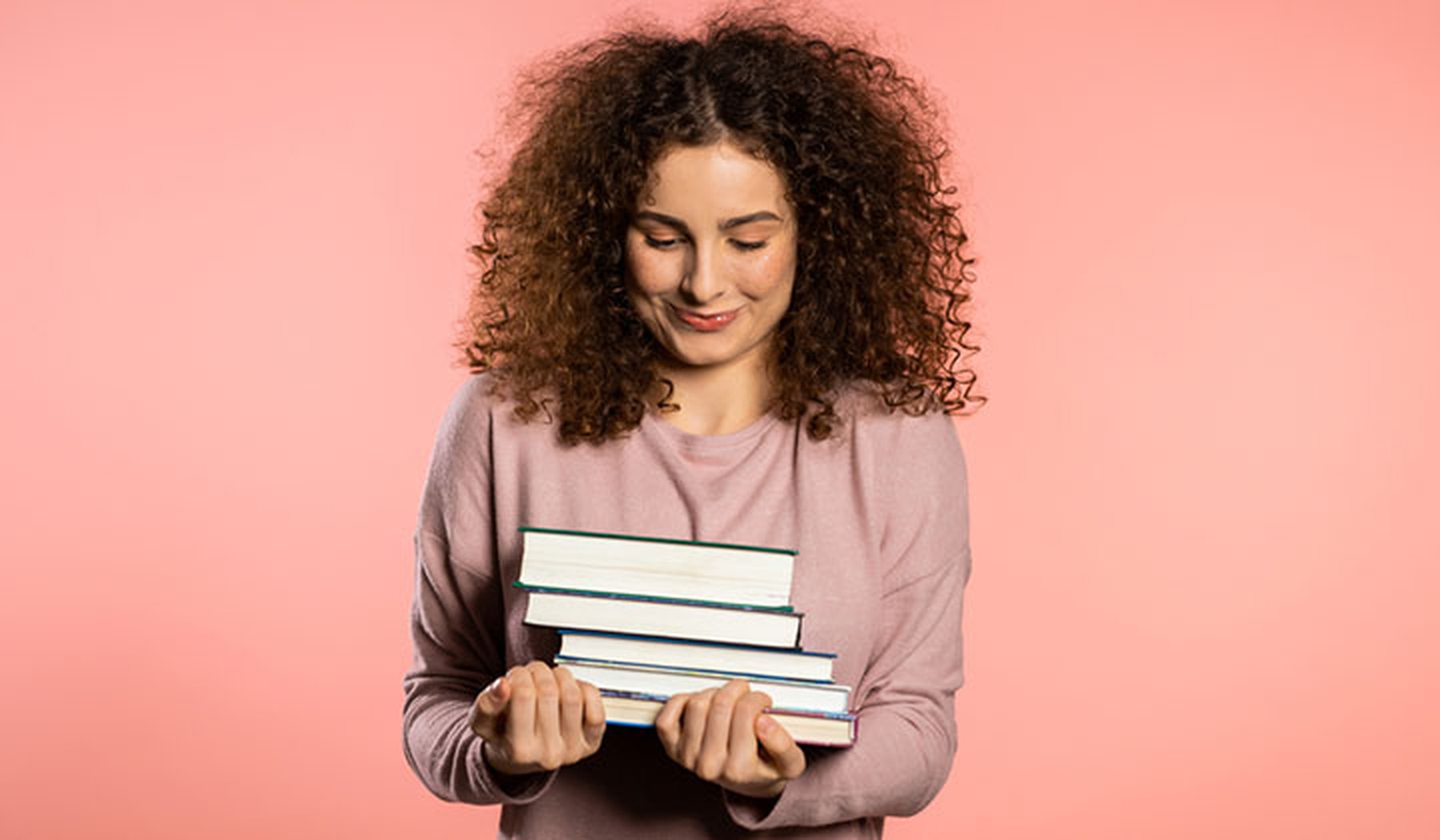 Chica jóven con varios libros entre sus brazos