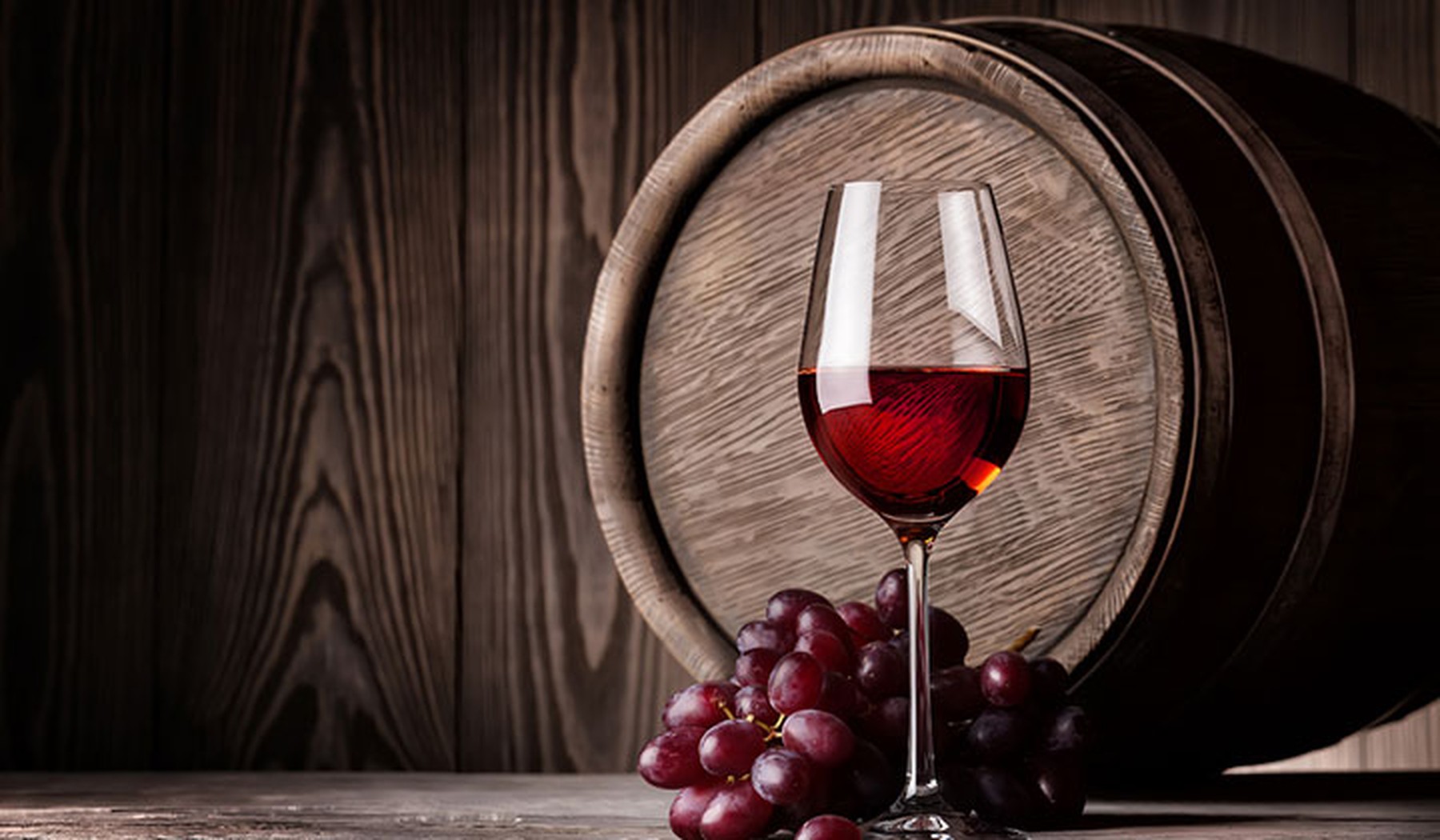 tonel de vino, copa de vino tinto y uvas rojas