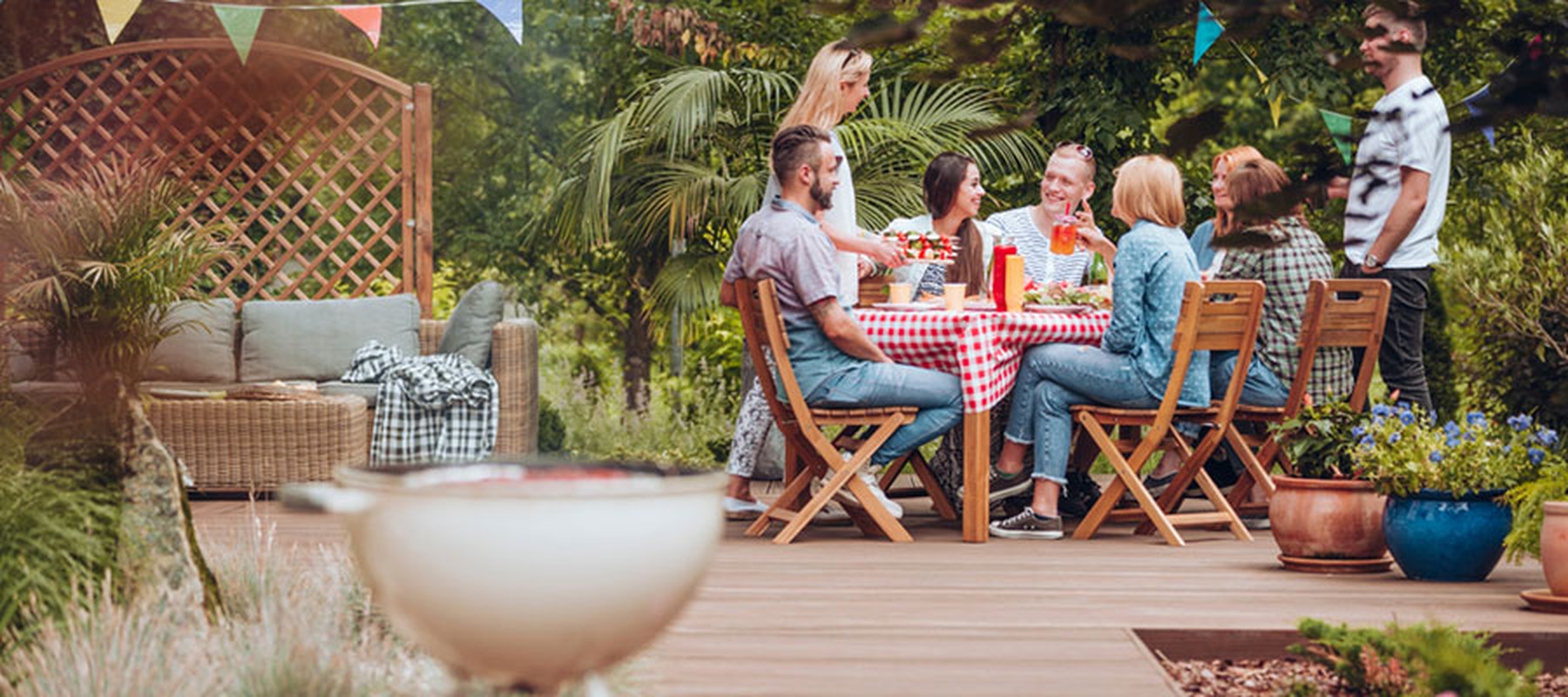 Grupo de amigos comiendo en una mesa de un bonito y decorado jardín