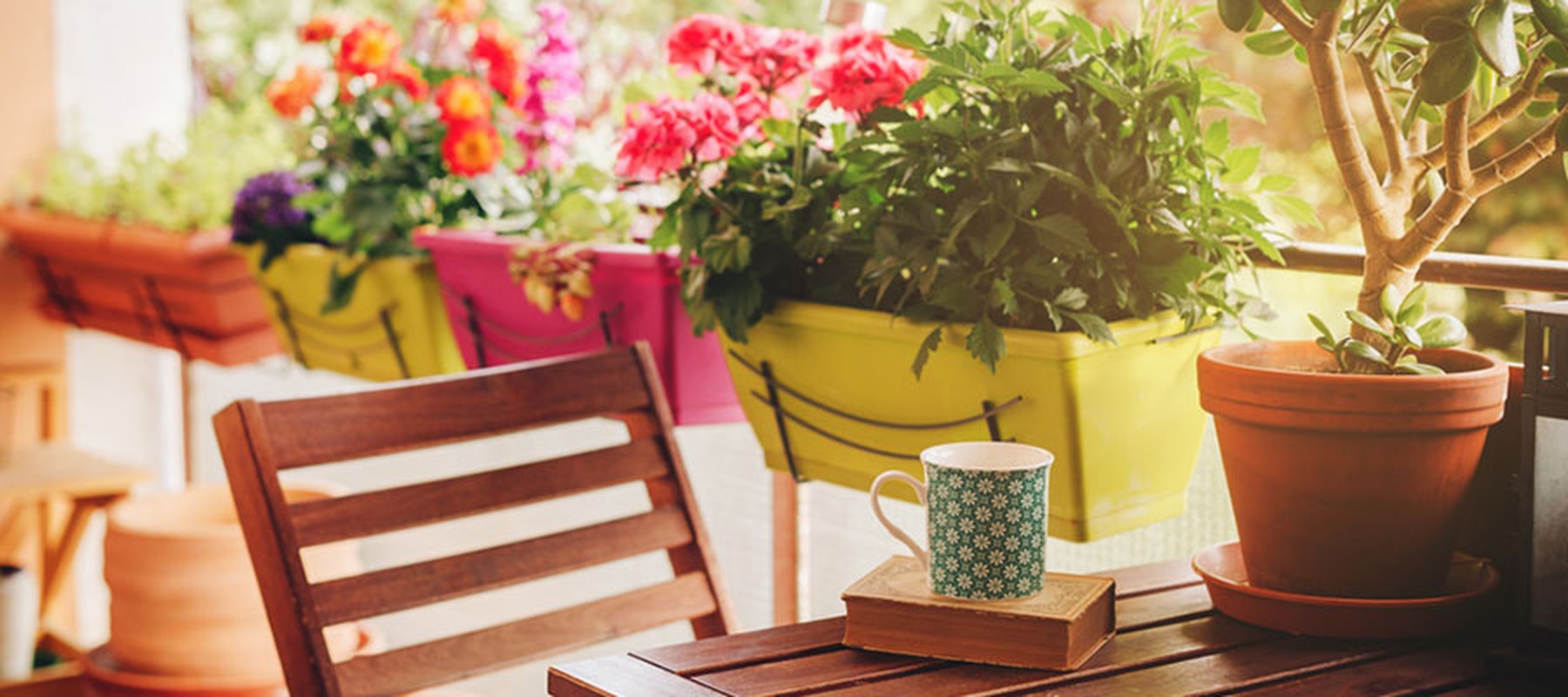 Macetas con flores junto a una mesa y silla de un balcón