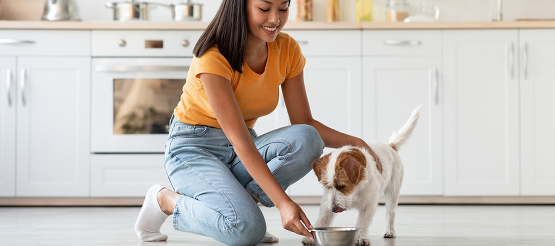 Mujer jóven ofreciendo cuenco de comida a su perro