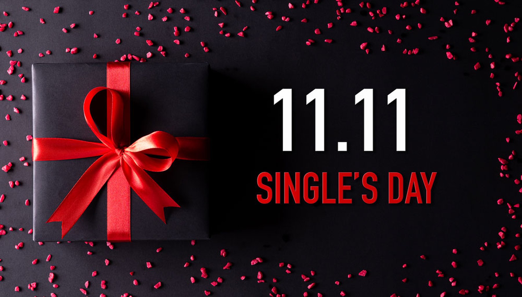 Fondo negro con piedras rojas y un paquete de regalo con un lazo rojo anunciando el 11.11 Single's Day