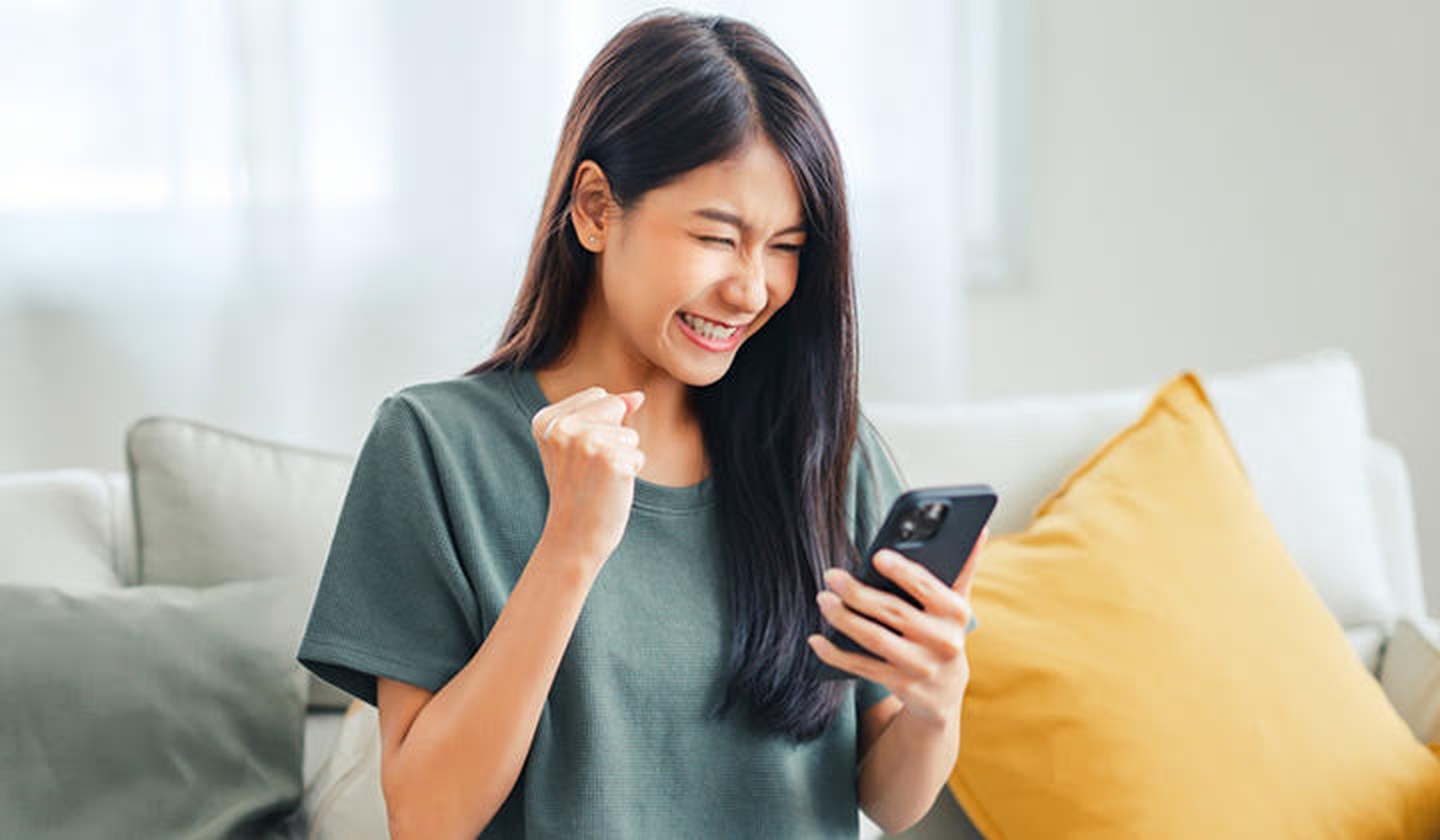 Mujer contenta tras conseguir ahorrar dinero en su compra online a través del móvil