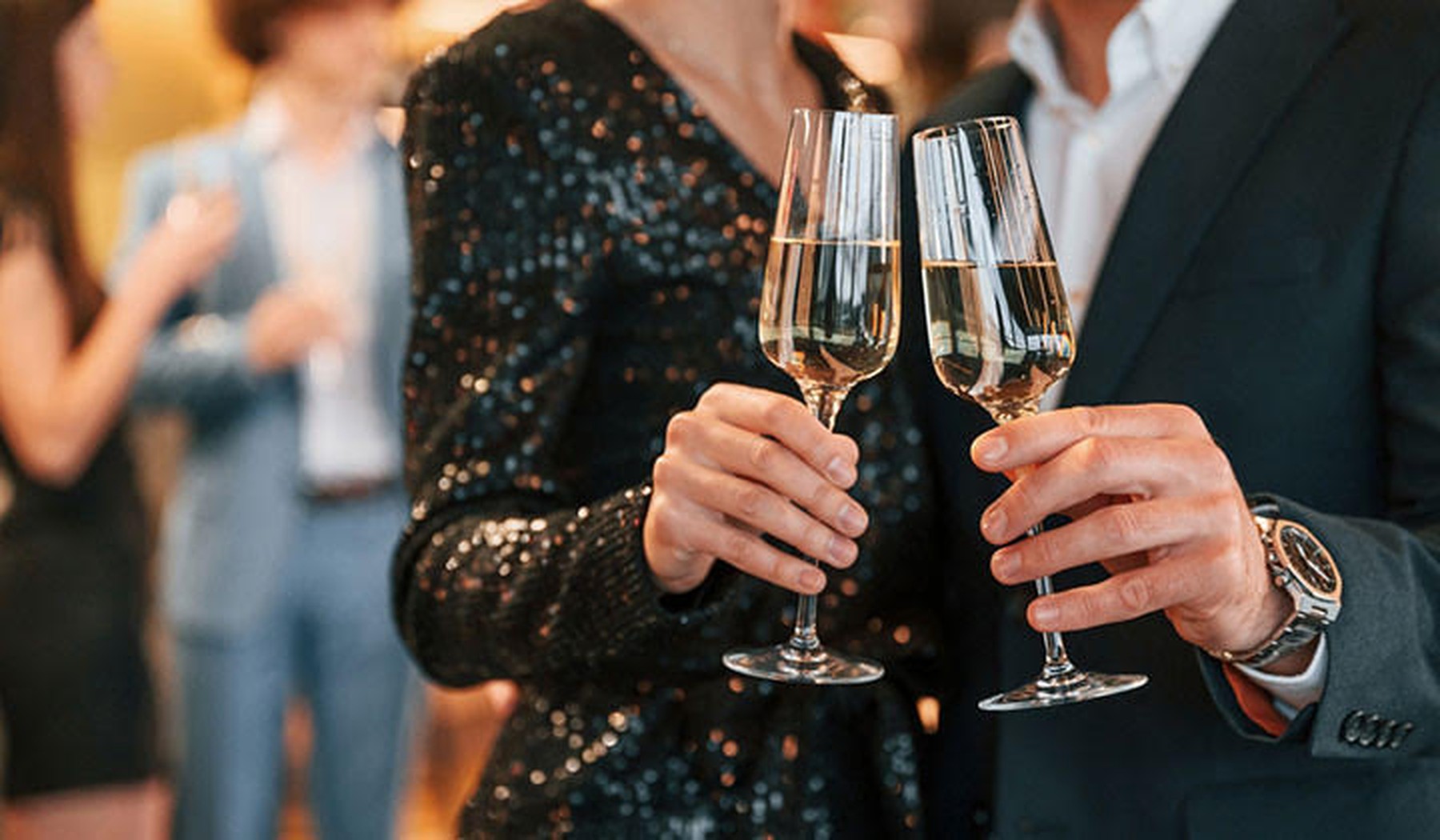Dos personas vestidas de fiesta brindando con copas de Champagne