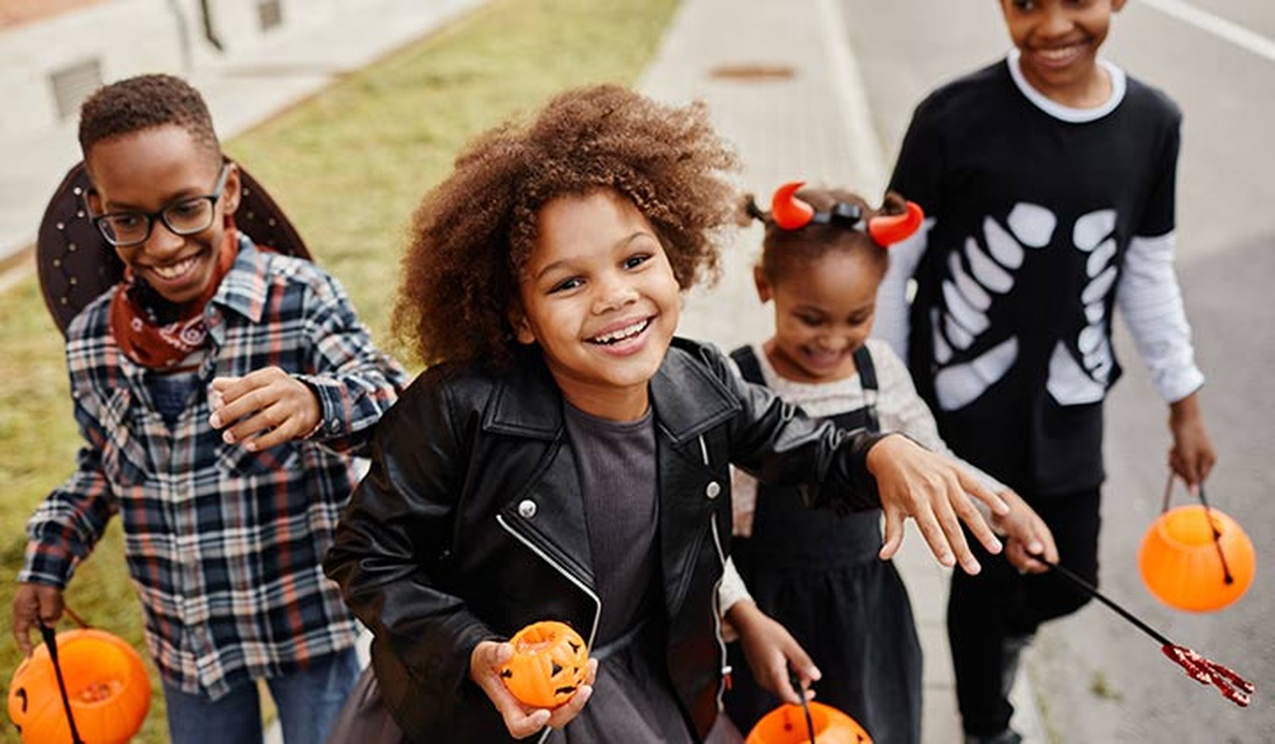 Grupo de niños sonrientes disfrazados de Halloween y corriendo hacia la cámara