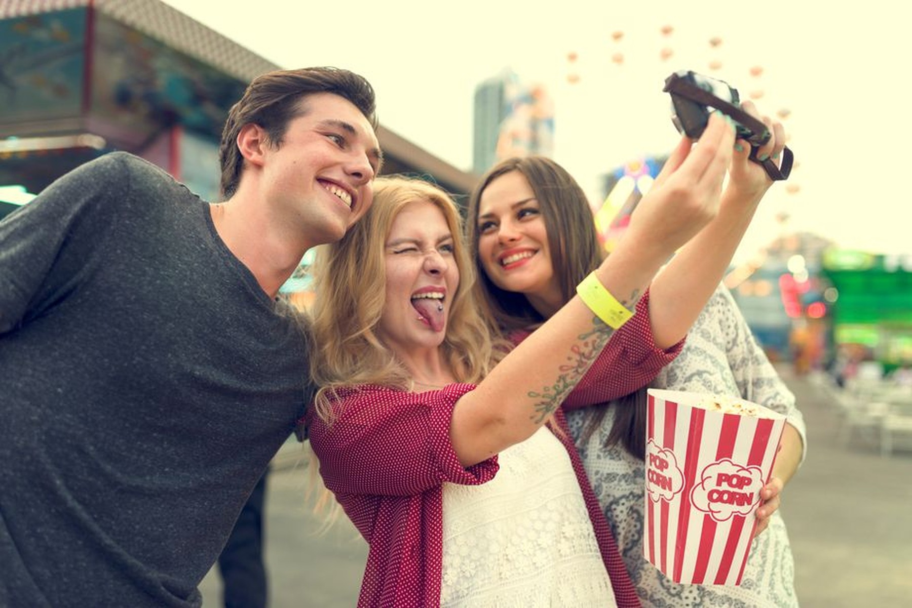 Grupo de tres amigos haciéndose un selfie a las puertas de un cine 