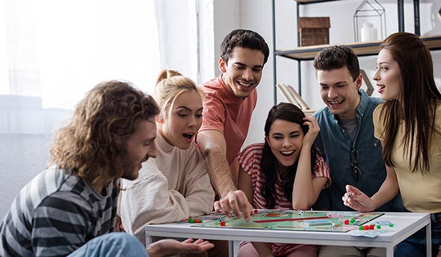 Grupo de amigos jóvenes jugando al Monopoly en su casa