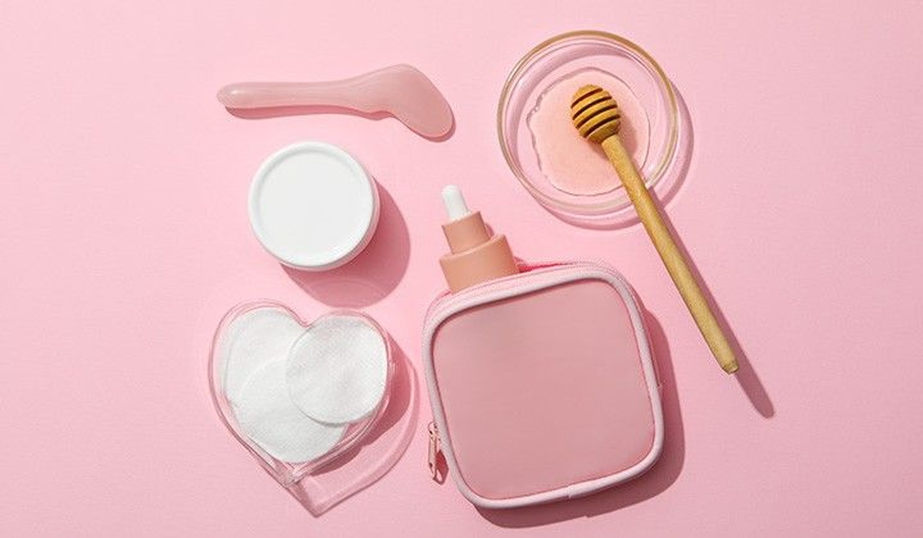 Objetos y productos para el cuidado de la piel sobre un fondo rosa