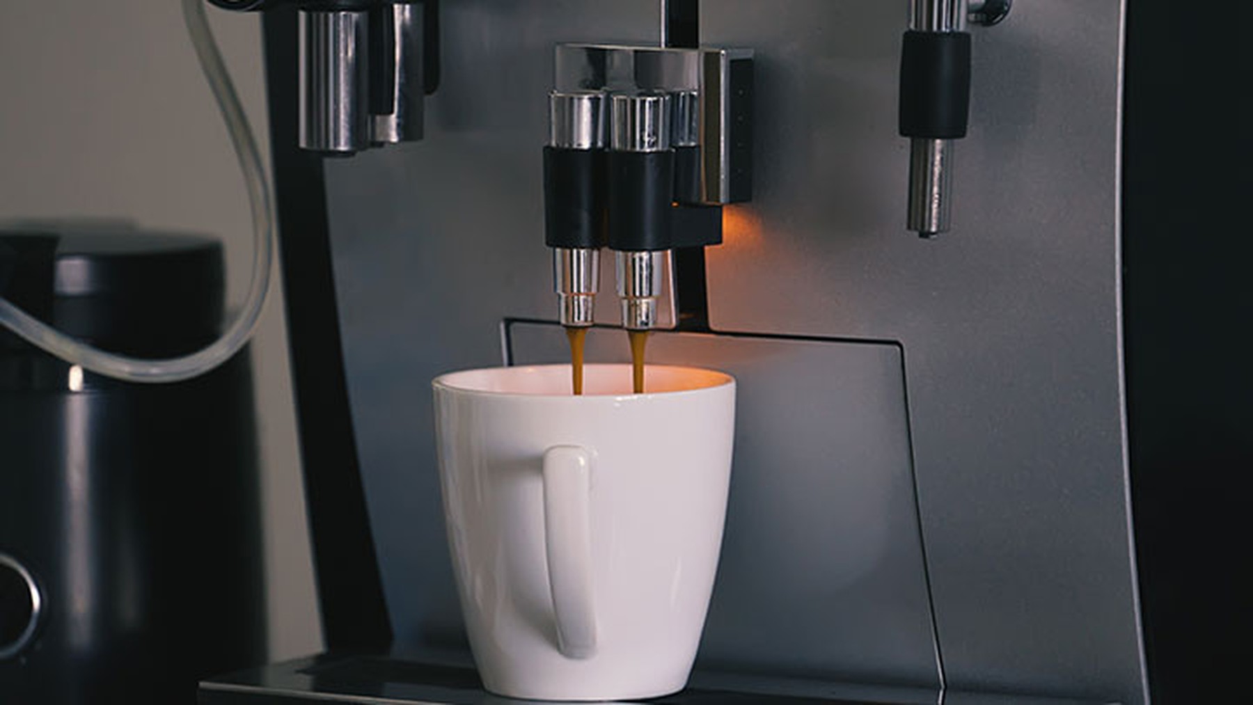 Cafetera automática echando café en una taza blanca