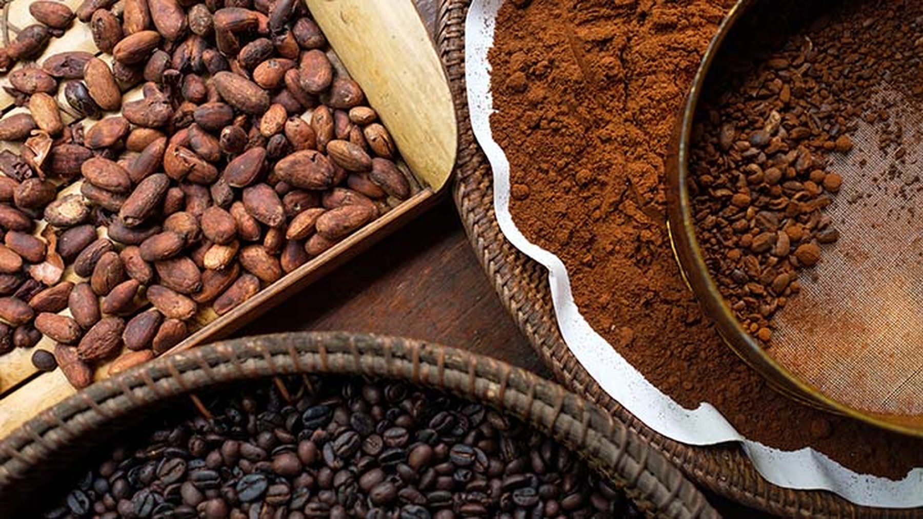 Diferentes tipos de café en grano y molido en diferentes recipientes sobre una mesa de madera