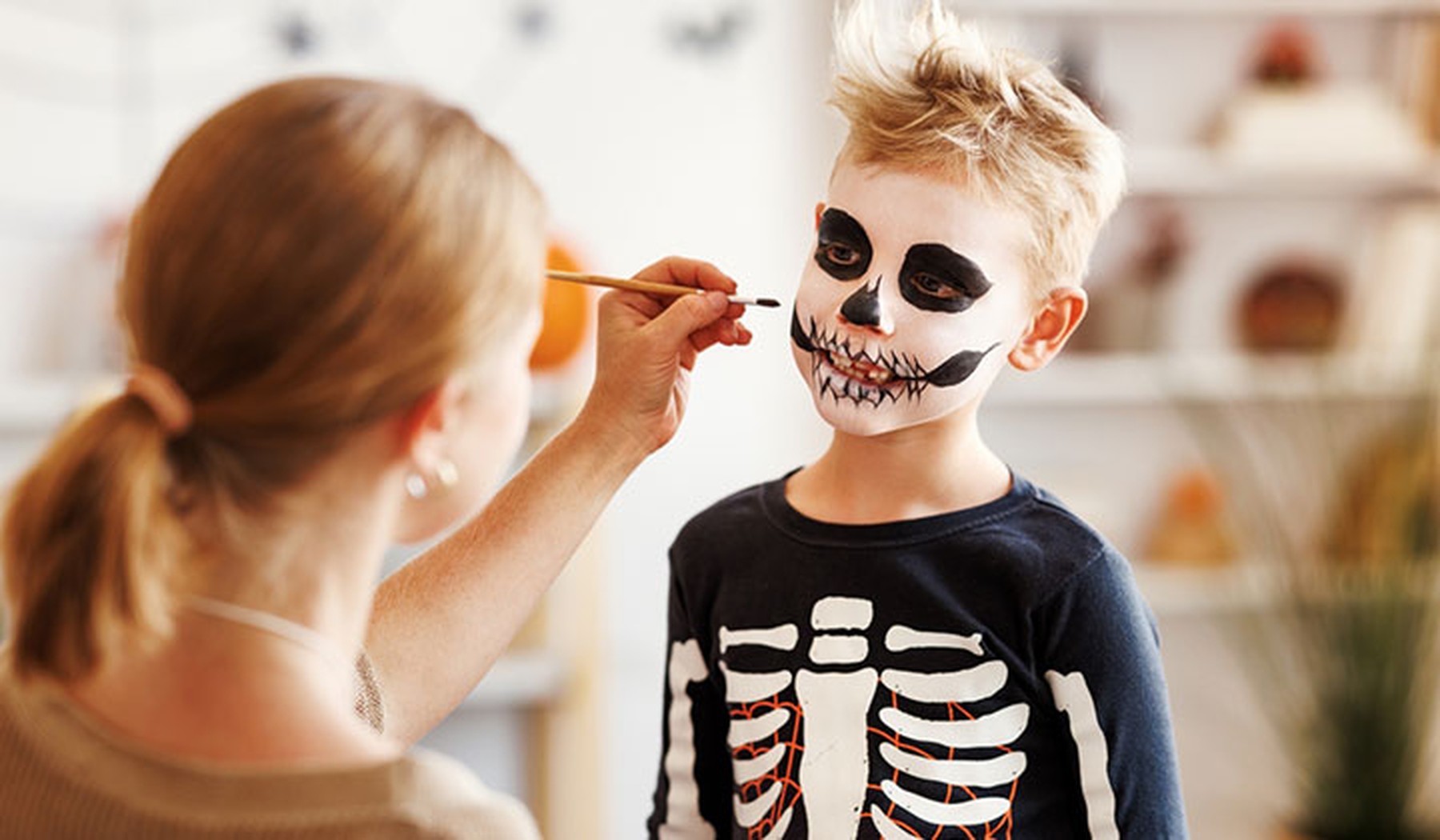 Mujer maquillando a un niño de esqueleto