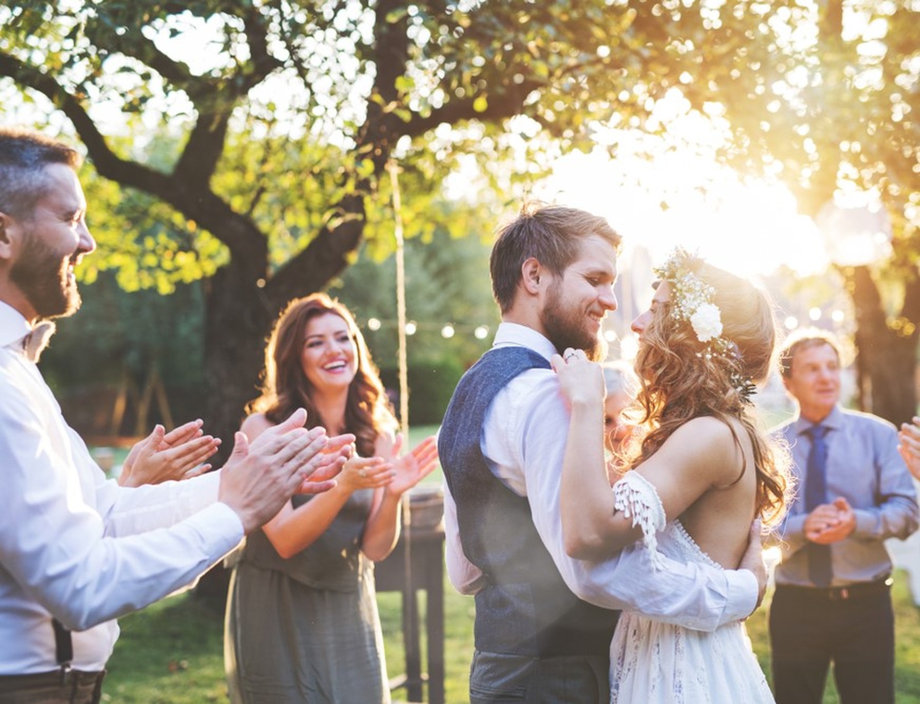 Una pareja de recién casados bailando en su boda con los invitados aplaudiendo