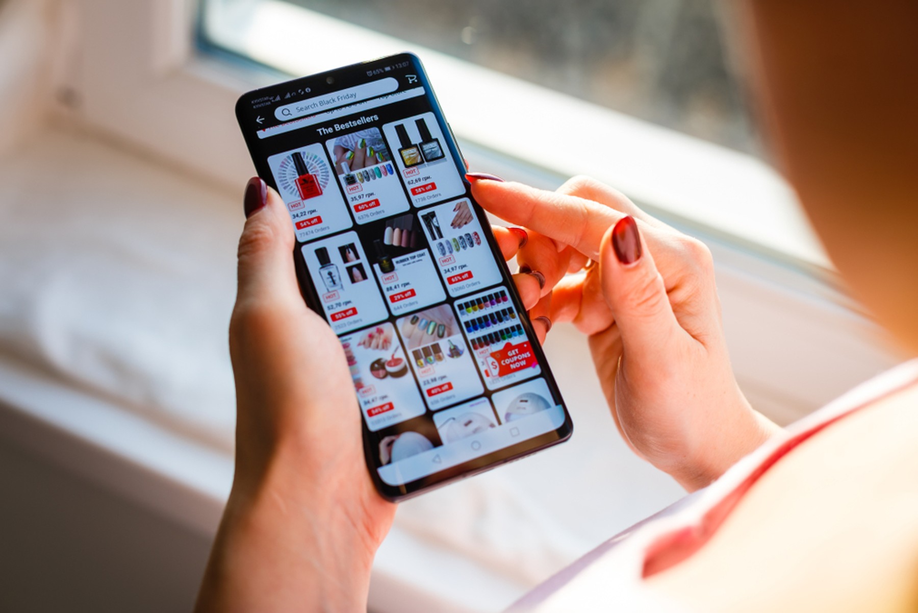 Mujer con las uñas rojas navegando por la web de AliExpress con su smartphone