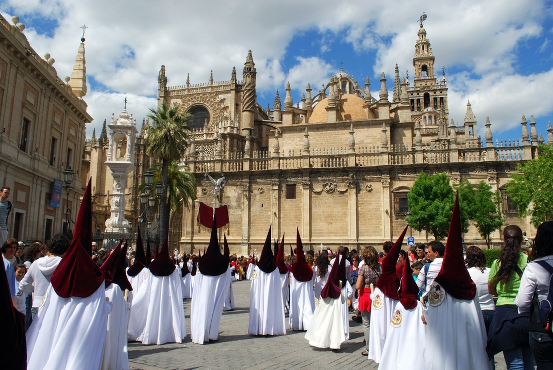 Procesión de Semana Santa en andalucía con nazarenos con capuchones granates y túnicas blancas