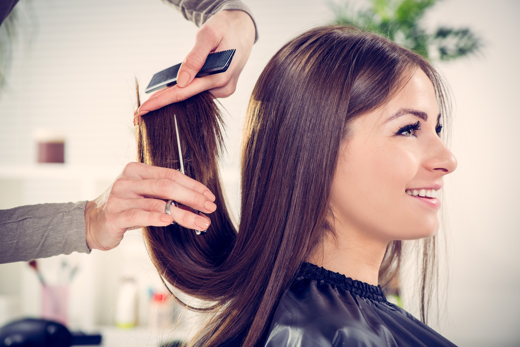 Mujer castaña sonriente mientras le cortan las puntas del pelo