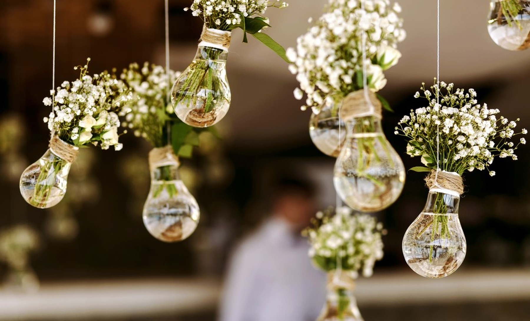 Bombillas con flores blancas secas dentro a modo de jarrón colgando de un techo